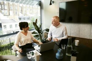 Deux professionnels participant à une réunion d'équipe dans un bureau londonien moderne avec une grande vue sur la fenêtre.