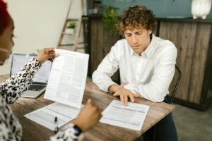 Deux professionnels examinent des documents dans un bureau, concentrés sur des tâches analytiques.
