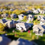 Photographie aérienne en mode tilt-shift d'un quartier de banlieue avec des pelouses vertes et des routes.